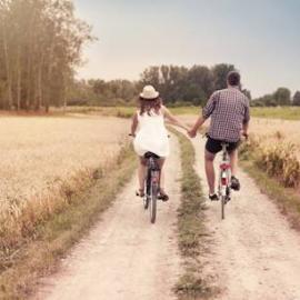 A couple, riding bikes while holding hands